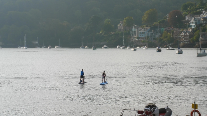 Paddleboarders with a dog on board on the Dart River in Dartmouth, Devon.