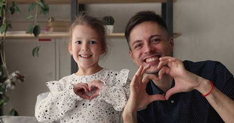 Young father and little 5s adorable daughter smiling looking at camera showing symbol making with fingers heart shape sign of love. Concept of blood donation and save life, volunteering, family bond