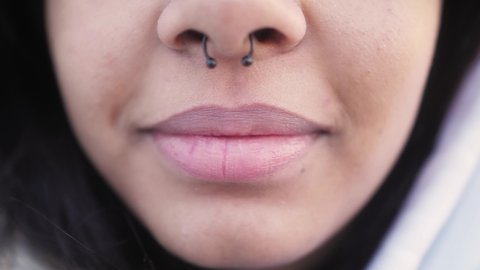 Close up of black girl wearing nose septum ring. Close up of lips and nose. Smiling mixed race woman. Feminine beauty.