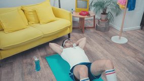 Sportsman doing abs on fitness mat in living room, retro sport concept