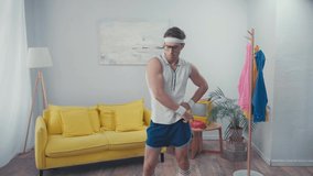 Front view of energetic sportsman with hand on hip, dancing in living room