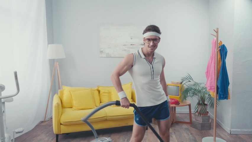 Energetic sportsman wagging hips, while vacuum cleaning living room Royalty-Free Stock Footage #1062673741