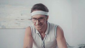 Sportsman in eyeglasses training on exercise bike in living room