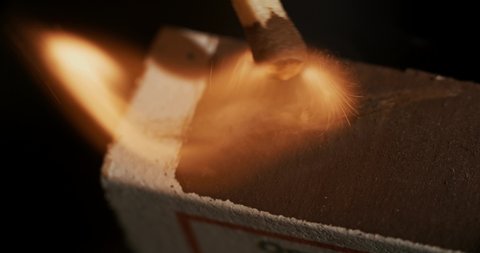 Hand spark off a wooden sticks in a match box. Glowing fire. Matches lighting at dark background in slow motion. Bright burn macro close up.