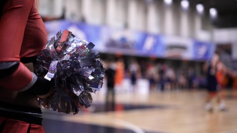 Close up of cheerleader girl body part while game. Female hands with pompoms shaking in the air. Concept of team games, professional sport concept.