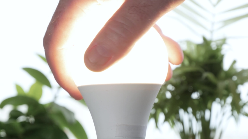 Man Rotates with His Hand a Led Bulb in Its Electrical Socket Opening the Light in the Room Royalty-Free Stock Footage #1062686224