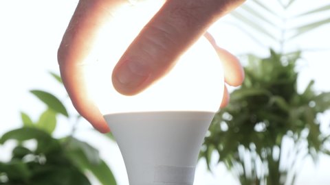 Man Rotates with His Hand a Led Bulb in Its Electrical Socket Opening the Light in the Room