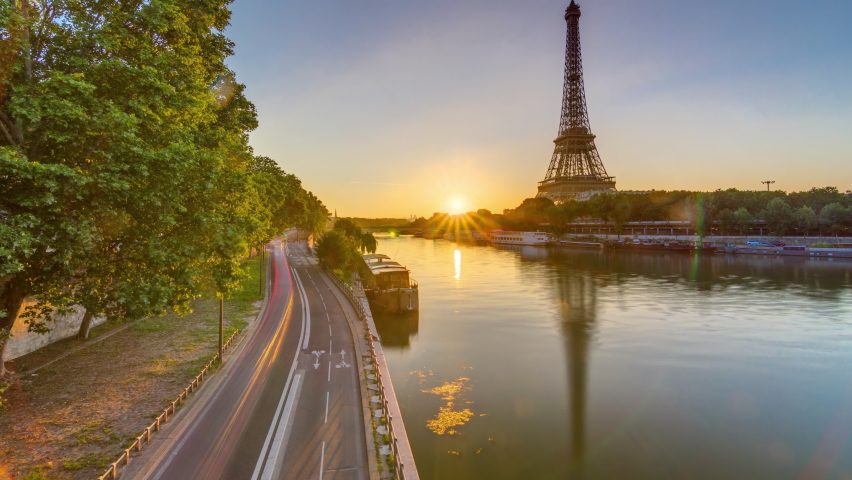 Eiffel Tower and the Seine river at Sunrise timelapse, Paris, France. Morning view from Bir-Hakeim bridge with reflections on water and traffic on the street