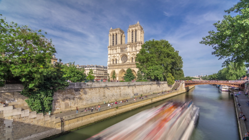 Front facade of cathedral of Notre Dame de Paris, with river and waterfront timelapse hyperlapse. Blue cloudy sky at summer day