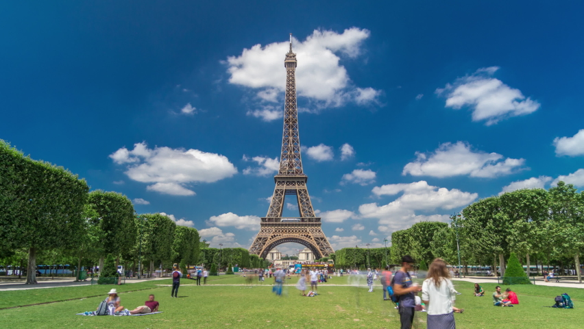 Eiffel Tower on Champs de Mars in Paris timelapse hyperlapse, France. Blue cloudy sky at summer day with green lawn and people walking around Royalty-Free Stock Footage #1062687001