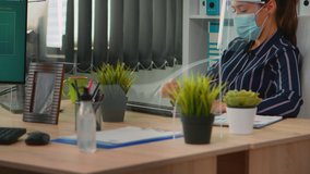 Entrepreneur with mask during coronavirus pandemic working in new normal business office discussing with coworker analysing financial data. freelancer respecting social distance in corporate company. - Powered by Shutterstock - Get 15% off with code: PIKWIZARD15