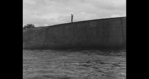 1941 Pearl Harbor: Submarine in the water. Men standing on keel of submarine.