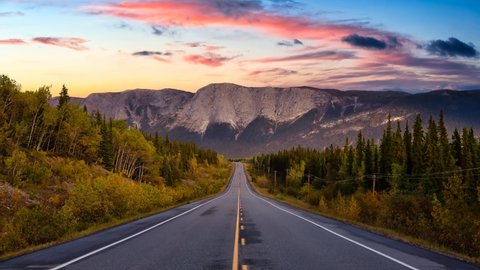 Cinemagraph Continuous Loop Animation. Scenic Road surrounded Rocky Mountains on a Cloudy Fall Season in Canadian Nature. Colorful Sunset Artistic Render. Taken near Whitehorse, Yukon, Canada.