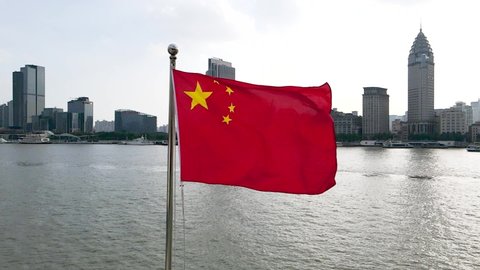 Chinese National Flag blowing around famous landmark, the Bund, in downtown Finance business Chinese culture concept b roll footage China's 5 star national flag in the wind in downtown Shanghai China