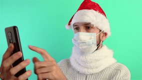 bearded man in santa hat and protection face mask using smartphone video chat calling online streaming