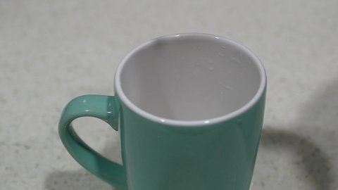 Filling up a ceramic cup with clean drinking water from kitchen faucet