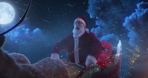 Senior man in Santa Claus costume grasping reins and urging reindeer forward then stopping sled against clouds and moon in night sky on Christmas eve
