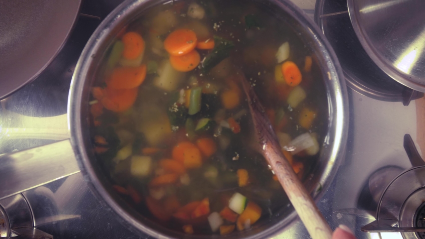 stirring a pot of vegetable soup top view. Minestrone soup boiling in the pot. Vegetarian healthy meal for dinner. Ready vegetable meal for lunch, hot and cozy soup for dinner at home Royalty-Free Stock Footage #1062706288