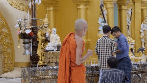 December 2019, Yangon, Myanmar, Asia: A monk in orange clothing is walking inside the Scwedagon Pagoda complex 