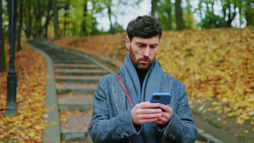 Close up young stylish man in autumn park use phone stand coughs feel unhealthy with electric scooter. Ecological transportation. Virus illness allergic. Portrait pain tired. Slow motion
