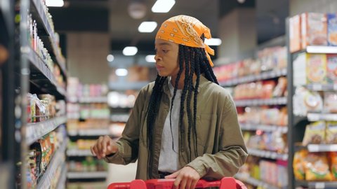 African american stylish woman observing canned foods section in grocery store. Supermarket customer. Marketplace. Customers, consumerism. Shopping concept.
