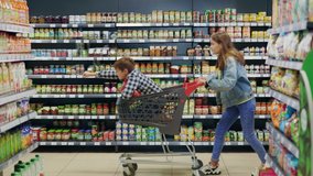 Happy excited siblings having fun riding cart in supermarket produce section running away from parents. Entertainment. Weekend shopping. Families. - Powered by Shutterstock - Get 15% off with code: PIKWIZARD15