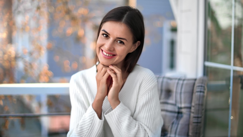 Portrait of cozy beauty female in white warm sweater posing at outdoor terrace of countryside house. Face of cute brunette lady enjoying warm autumn day on balcony. Shot on RED Raven 4k Cinema Camera