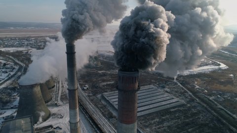 Puffs of dark smoke dirty clouds of toxic vapor are emitted from pipes. Epic winter factory production. Industrial plant many buildings. Environmental problem pollution. Drone flies close into smoke