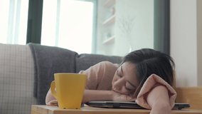 4K Beautiful Asian woman freelance sitting on the floor at apartment living room and take a nap during working on laptop computer. Businesswoman working online at home for success in business project