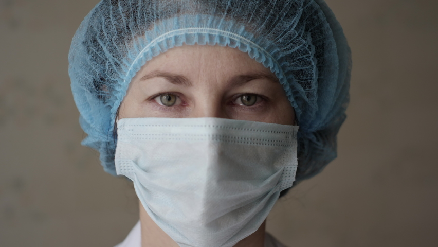 Sad Sick, Overworked Serious Female Health Care Worker Looking at Camera. Portrait Close Up Doctor Nurse Wearing Protective Mask, Protection Against Contagious Corona Virus Disease COVID-19. Royalty-Free Stock Footage #1062720256