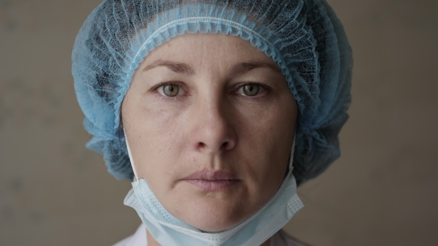 Sad Sick, Overworked Serious Female Health Care Worker Looking at Camera. Portrait Close Up Doctor Nurse Wearing Protective Mask, Protection Against Contagious Corona Virus Disease COVID-19. Royalty-Free Stock Footage #1062720256