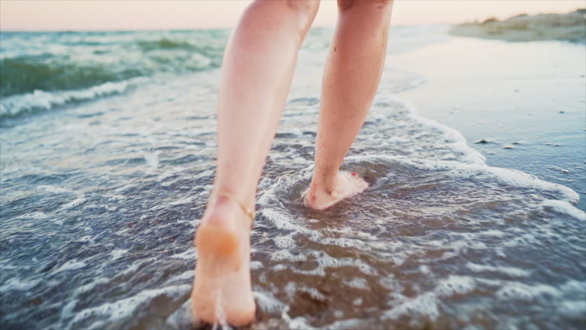 Legs of girl walking barefoot on wet sandy island beach. Beautiful feet of young woman near sea on sunset or sunrise. Slow motion. | Shutterstock HD Video #1062721123