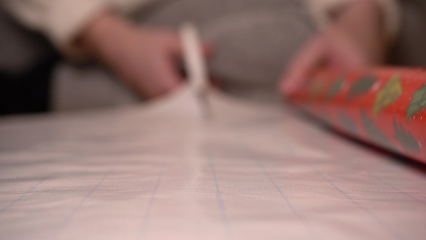 Woman cuts wrapping paper with scissors.  