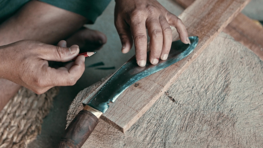 Nepalese craftsman measuring wooden plank for kukri knife sheath