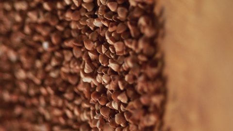 Buckwheat grains on a delicious background and wood floor passes in front of the camera in slow motion. Macro, 4K, Phantom Camera,Very Close-up, 900 fps video.Video for the vertical story.