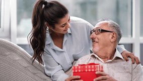 Caring daughter granddaughter giving gift box to mature father grandfather having positive emotion. Happy family making surprise present celebrate holiday together. Shot on RED Raven 4k Cinema Camera - Powered by Shutterstock - Get 15% off with code: PIKWIZARD15