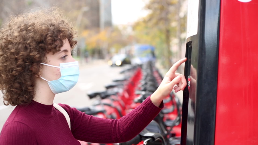 Woman in face mask renting a bike in city