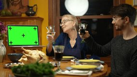 Family having a video call with relative during thanksgiving dinner, happy family greeting a remote guest. Concept of remote holiday meal.