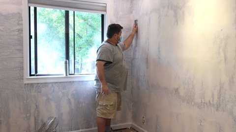 Contractor using sand trowel sanding the drywall on the wall