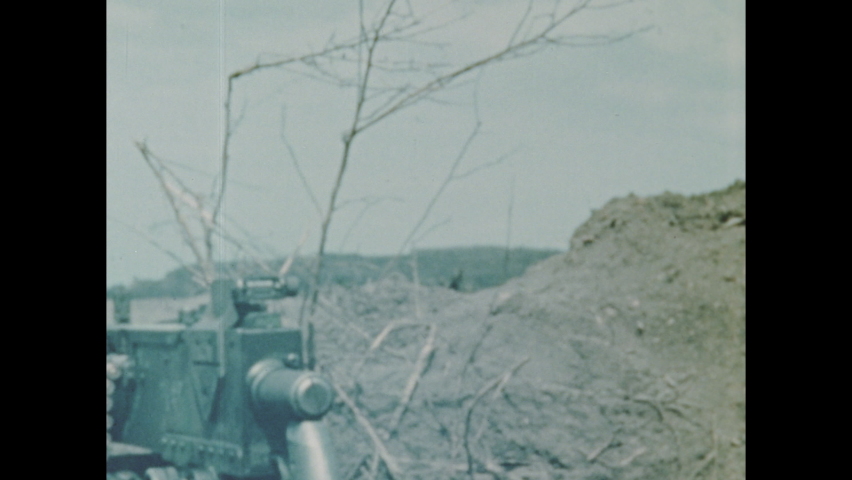 1940s Iwo Jima: Heavy machine gun sits in hills of Iwo Jima. Soldier helps injured colleague walk across beach.
