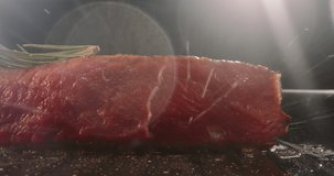 Close up shot of juicy raw steak being fried with rosemary on top. Tasty meat being prepared for serving, cooked with passion - food and drink 4k footage