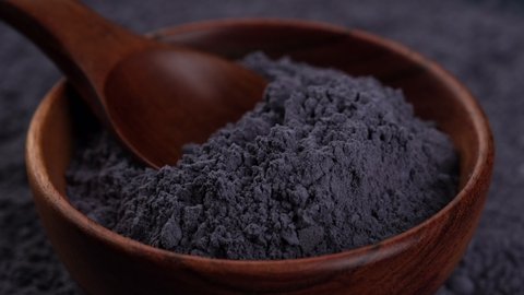 blue butterfly pea powder in wooden bowl close up.  superfoods
