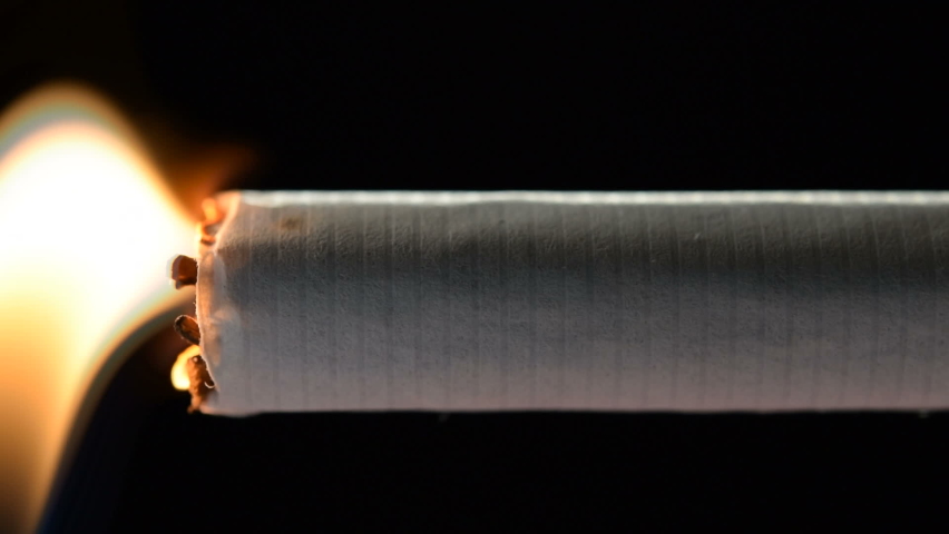 Lit and burning cigarette with smoke on black background | Shutterstock HD Video #1062743017