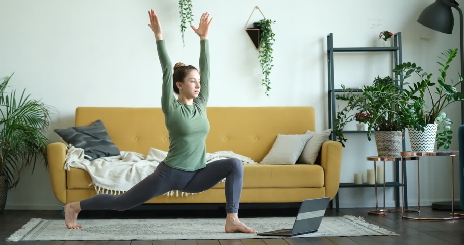 Online sport fitness yoga training workout. young woman and doing exercises opposite laptop at home. yoga asanas. woman practicing yoga concept natural balance between body and mental development. | Shutterstock HD Video #1062750274