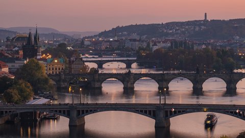 Prague, Czech Republic, zoom in time lapse view of Prague cityscape showing medieval bridges and boats on the Vltava river at sunset. 