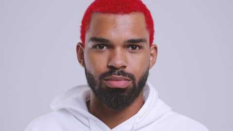 Close up of shocked amazed young bearded black african american man with funky red hair 20s in streetwear hoodie look aside camera say wow isolated on white background studio. People lifestyle concept