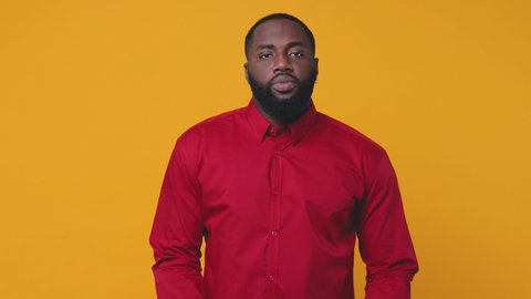 Smiling cheerful excited young bearded african american man 20s wearing red shirt isolated on bright yellow color background studio. People lifestyle concept. Looking camera dancing clenching fists