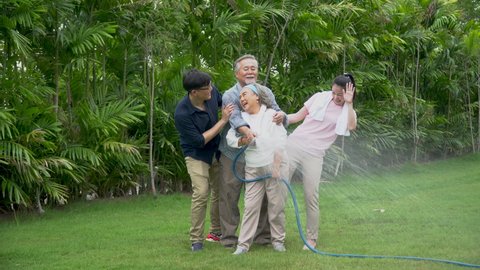 happy asian family watering the plants  in the front lawn at home  Spend time together lifestyle in garden
