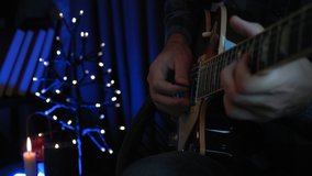 Musician is playing solo guitar part on electric guitar. Close up of male hands play on strings with guitar pick. Guitarist is performing lyric love song on guitar in recording vocal studio