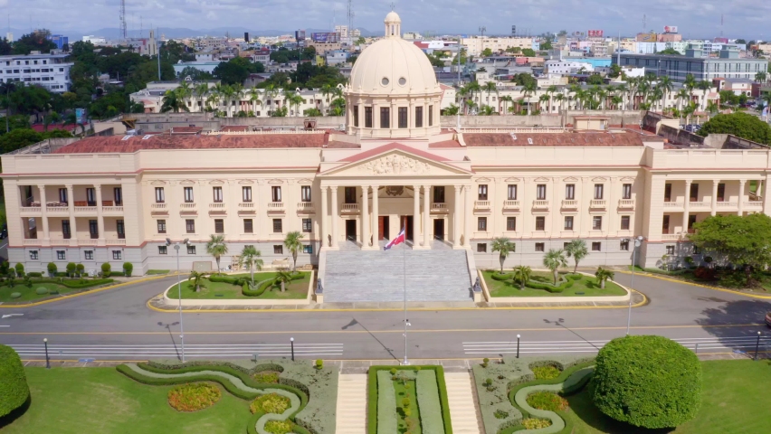 Backward flight with drone in the Presidential Palace of Dominican Republic, beautiful green garden, sunny day